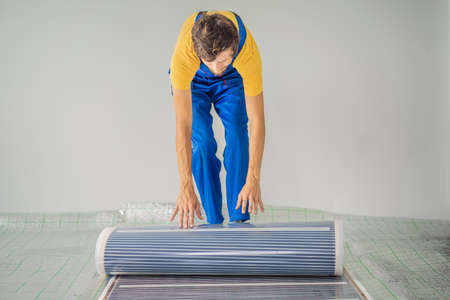 Master installs film warm floor in the room. Floor heating installationの写真素材
