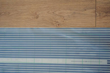 Wooden floor, laminate on a warm film floor. Comfort in home. Warm floor concept. Heating in the house and apartmentの写真素材