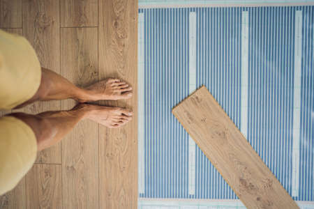 Wooden floor, laminate on a warm film floor. Comfort in home. Warm floor concept. Heating in the house and apartmentの写真素材