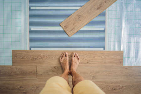 Wooden floor, laminate on a warm film floor. Comfort in home. Warm floor concept. Heating in the house and apartmentの写真素材