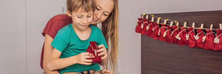 BANNER, LONG FORMAT Smiling boy sitting on a bed opening first present from advent calendar. Winter seasonal tradition. Copy spaceの写真素材