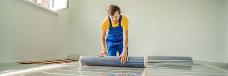 Master installs film warm floor in the room. Floor heating installation BANNER, LONG FORMATの写真素材