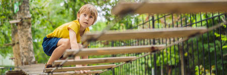 Little boy in a rope park. Active physical recreation of the child in the fresh air in the park. Training for children BANNER, LONG FORMATの写真素材