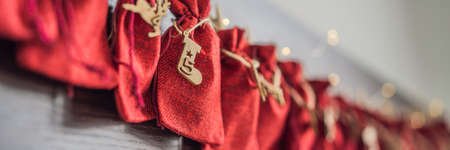 Advent calendar red bags on a rope hang on a childs bed BANNER, LONG FORMAT