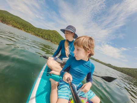 happy family of two, mother and son, enjoying stand up paddling during summer vacationの写真素材