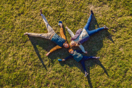 family top view. lying on the grass. sunny day. in green nature together. Aerial view Drone photographyの写真素材