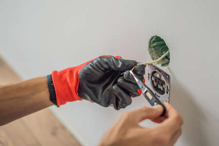 Master electrician installs a socket in the house