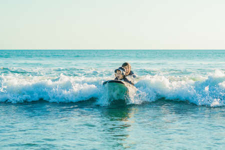 Father teaching his young son how to surf in the sea on vacation or holiday. Travel and sports with children conceptの写真素材