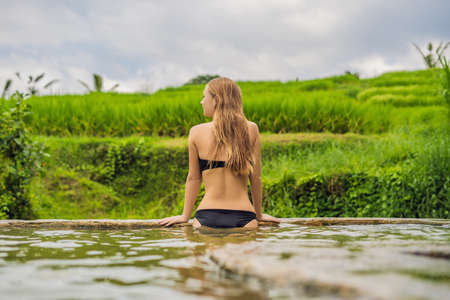Young woman tourist in Belulang Hot Springs in Bali on the background of rice terracesの写真素材