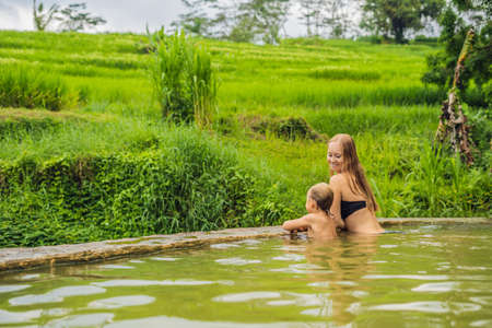 Mom and son travelers in Belulang Hot Springs in Bali on the background of rice terraces Traveling with children conceptの写真素材