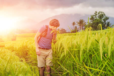 Young man traveler on Beautiful Jatiluwih Rice Terraces against the background of famous volcanoes in Bali, Indonesia with sunlightの写真素材