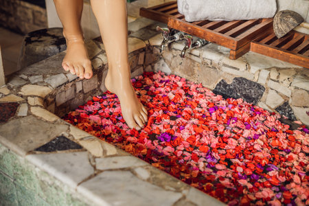 Attractive Young woman in bath with petals of tropical flowers and aroma oils. Spa treatments for skin rejuvenation. Alluring woman in Spa salon. Girl relaxing in bathtub with flower petals. Luxury spa and skin care.の写真素材