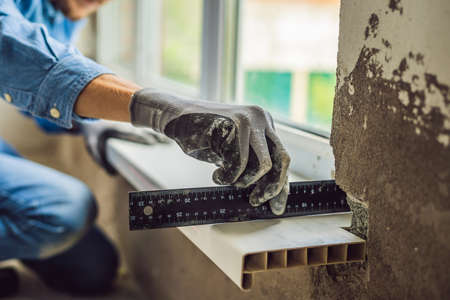 Man in a blue shirt does window installationの写真素材