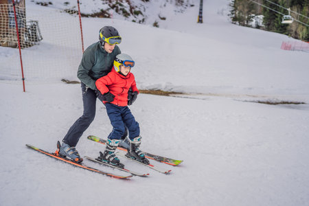 Boy learning to ski, training and listening to his ski instructor on the slope in winterの写真素材