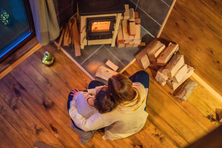 Mom and son spend time by the fireplace in Glamping. Rest in the mountains in Glamping. Cozy fireplace in a mountain houseの写真素材