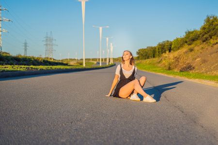 Beautiful young woman posing on a road over picturesque landscape.の写真素材