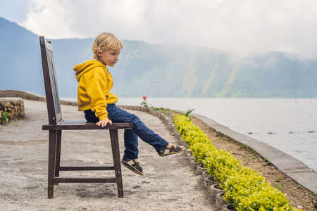 Boy at the lake Bratan and the mountains covered with cloudsの写真素材