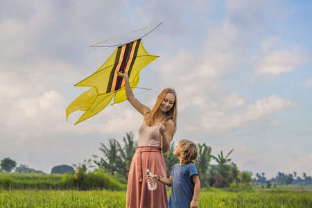 Mom and son launch a kite in a rice field in Ubud, Bali Island, Indonesiaの写真素材