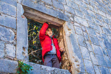 Young tourist boy enjoying a view of Kotor Bay, Montenegro. Kotor Old Town Ladder of Kotor Fortress Hiking Trail. Aerial drone viewの写真素材