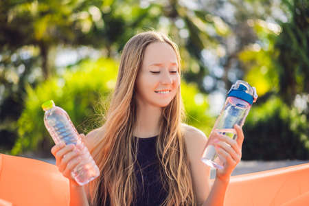 Summer lifestyle portrait of pretty girl sitting on the orange inflatable sofa selects a disposable...