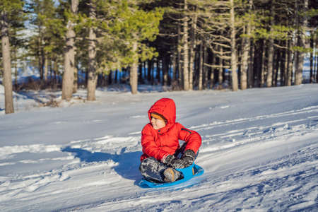 happy and positive little boy enjoying sledding and cold weather outdoor, winter fun activity conceptの写真素材