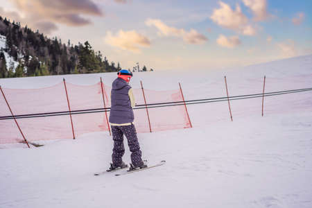 Woman skier climbs a mountain on a ski lift for beginnersの写真素材