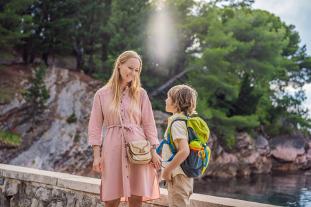Mom and son tourists walking together in Montenegro. Panoramic summer landscape of the beautiful green Royal park Milocer on the shore of the the Adriatic Sea, Montenegroの写真素材