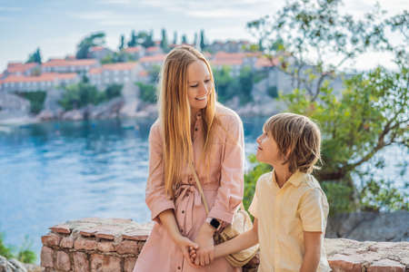 Mom and son tourists on background of beautiful view St. Stephen island, Sveti Stefan on the Budva Riviera, Budva, Montenegro. Travel to Montenegro conceptの写真素材