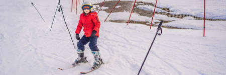 BANNER, LONG FORMAT Child skiing in mountains. Active toddler kid with safety helmet, goggles and poles. Ski race for young children. Winter sport for family. Kids ski lesson in alpine school. Little skier racing in snow.の写真素材