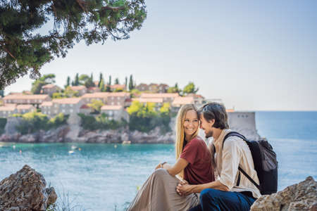 Man and woman tourists on background of beautiful view of the island of St. Stephen, Sveti Stefan on the Budva Riviera, Budva, Montenegro. Travel to Montenegro conceptの写真素材