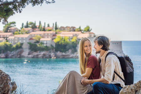 Man and woman tourists on background of beautiful view of the island of St. Stephen, Sveti Stefan on the Budva Riviera, Budva, Montenegro. Travel to Montenegro conceptの写真素材