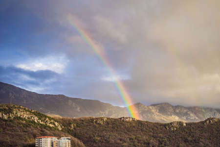 Rainbow over a green summer hills and mountainsの写真素材