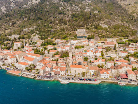 Scenic panorama view of the historic town of Perast at famous Bay of Kotor with blooming flowers on a beautiful sunny day with blue sky and clouds in summer, Montenegro, southern Europeの写真素材