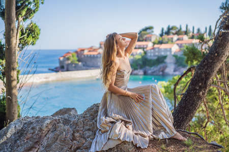 Woman tourist on background of beautiful view of the island of St. Stephen, Sveti Stefan on the...