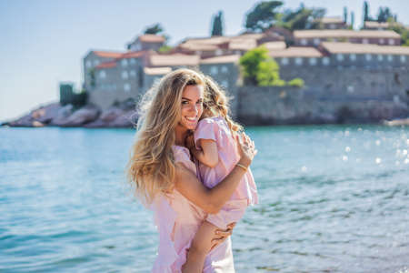 Mother and daughter tourists on background of beautiful view St. Stephen island, Sveti Stefan on the Budva Riviera, Budva, Montenegro. Travel to Montenegro conceptの写真素材