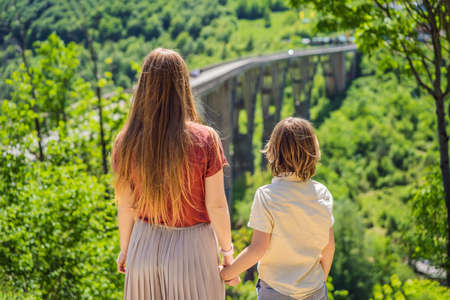 Montenegro. Mom and son tourists in background of Dzhurdzhevich Bridge Over The River Tara. Travel around Montenegro concept. Sights of Montenegroの写真素材