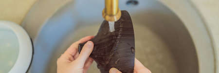 BANNER, LONG FORMAT Woman washing aroma diffuser in faucet. Aromatherapy Concept. Wooden Electric...