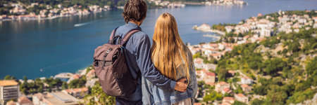 BANNER, LONG FORMAT Couple woman and man tourists enjoys the view of Kotor. Montenegro. Bay of...
