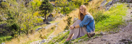 BANNER, LONG FORMAT Woman tourist enjoys the view of Kotor. Montenegro. Bay of Kotor, Gulf of Kotor, Boka Kotorska and walled old city.の写真素材