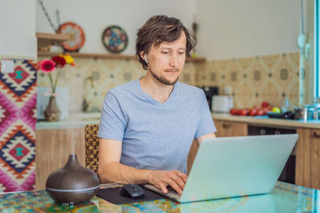 Essential oil diffuser on the table steaming while man using laptop
