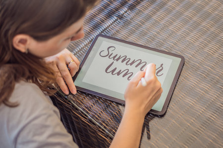Calligrapher Young Woman writes phrase on digital tablet. Inscribing ornamental decorated letters....