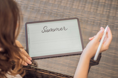 Calligrapher Young Woman writes phrase on digital tablet. Inscribing ornamental decorated letters. Calligraphy, graphic design, lettering, handwriting, creationの写真素材