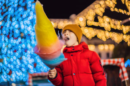Boy with cotton candy at christmas market. Happy child on Christmas market. Traditional leisure for families on xmasの写真素材