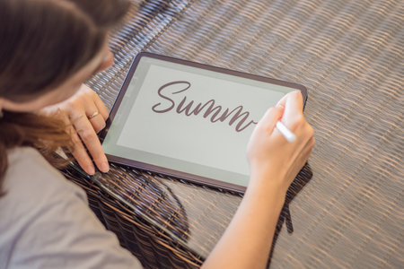 Calligrapher Young Woman writes phrase on digital tablet. Inscribing ornamental decorated letters. Calligraphy, graphic design, lettering, handwriting, creationの写真素材