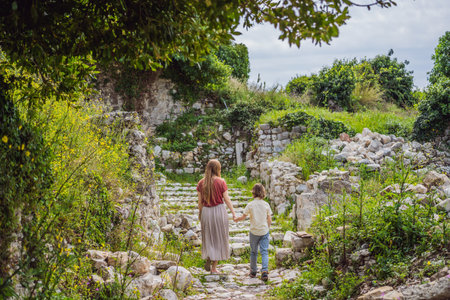 Mom and son tourists walks through the old town of Bar in Montenegro. Happy tourist walks in the mountains. Suburbs of the city of Bar, Montenegro, Balkans. Beautiful nature and landscapeの写真素材