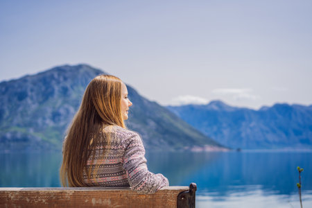 A woman sits on a bench and admires the view of the Bay of Kotor. Montenegroの写真素材