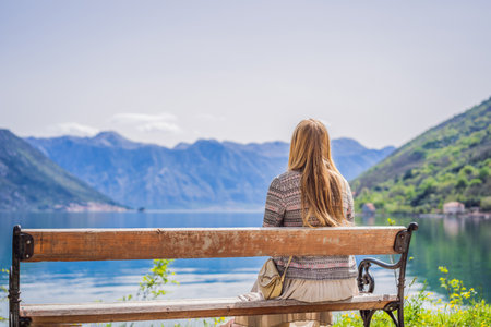 A woman sits on a bench and admires the view of the Bay of Kotor. Montenegro