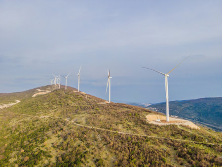 Wind turbines on beautiful sunny summer autumn mountain landsape. Curvy road through mountain Eolic park. Green ecological power energy generation. Wind farm eco fieldの写真素材