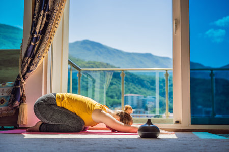 Mindful healthy woman practicing yoga at home. Sitting on the floor doing yoga for mental balance relaxing on stress. Enjoying time uses an aroma diffuserの写真素材