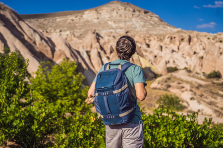 Young man exploring valley with rock formations and fairy caves near Goreme in Cappadocia Turkey